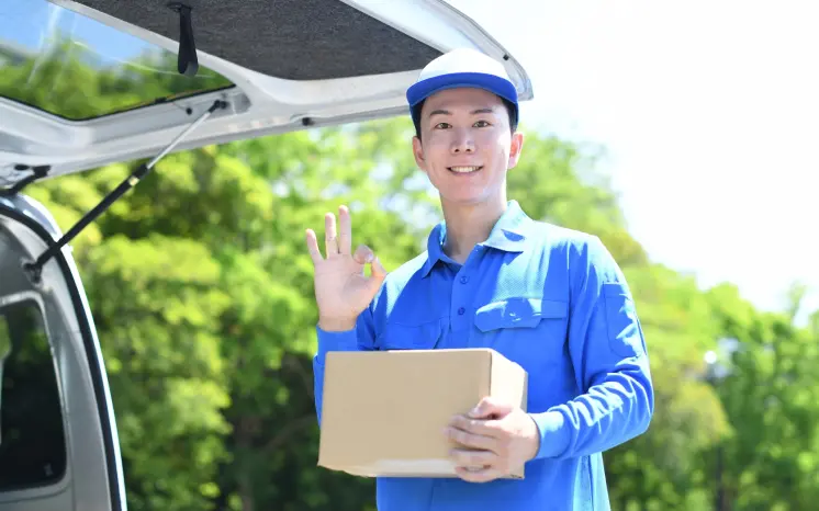 荷物を持ちOKサインをする軽貨物ドライバー