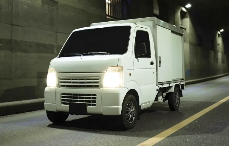 夜間のトンネルを走行する軽貨物車両